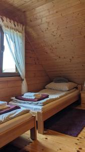 two beds in a log cabin with a window at Domki u Jacka in Wilkasy