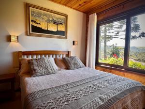 a bedroom with a bed and a large window at Pousada Rural Vista Alegre in Bom Jardim da Serra