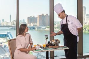 Uno chef in piedi accanto a una donna a un tavolo di The St. Regis Cairo a Il Cairo