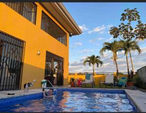 una persona en una piscina junto a un edificio amarillo en Casa del Sol en Parrita