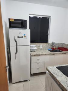 a kitchen with a white refrigerator and a microwave at Comfort 302 - 4 Quartos no Centro in Sete Lagoas