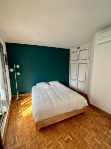 1 dormitorio con 1 cama grande y pared verde en Superbe appartement au porte de Paris et du salon des expositions, en Vanves