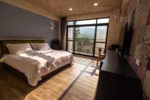 a bedroom with a bed and a large window at 晨煦行旅 in Lugu