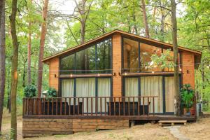 una cabaña en el bosque con porche y algunos árboles en Bizon Village en Zalesie Górne