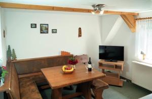 a living room with a wooden table and a television at Kammbaude Neuhermsdorf in Neuhermsdorf