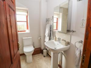 a white bathroom with a toilet and a sink at Seaview Cottage in Holt +16 photos