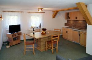 a kitchen with a wooden table with chairs and a television at Kammbaude Neuhermsdorf in Neuhermsdorf