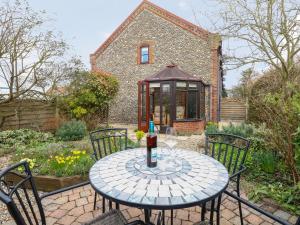a table with a bottle of drink on a patio at Seaview Cottage in Holt