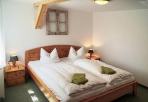 a bedroom with a bed with white sheets and green pillows at Kammbaude Neuhermsdorf in Neuhermsdorf