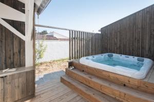 a hot tub on a deck with a fence at DUNE, villa avec piscine et spa / Proche plage in La Couarde-sur-Mer
