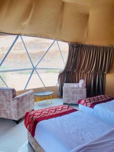 a bedroom with two beds and a large window at Maha Wadi Rum in Wadi Rum