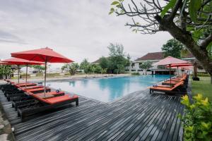 a swimming pool with red umbrellas and lounge chairs at Ombak Sunset in Gili Trawangan