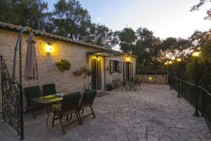 eine Terrasse mit einem Tisch, Stühlen und einem Sonnenschirm in der Unterkunft Su La Strata Villa by CorfuEscapes in Gaios