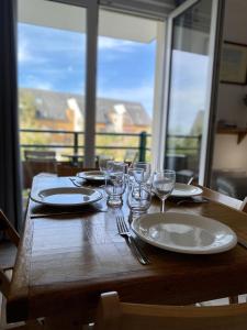 een houten tafel met borden en wijnglazen erop bij Wild Berry, oasis de tranquilité pour 4 personnes in Le Crotoy