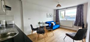 uma sala de estar com uma mesa e um sofá azul em Harlequin Apartments by Switchback Stays em Cardiff