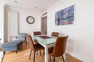 a dining room with a table and chairs and a clock at Gorgeous Kentish Town Flat in London