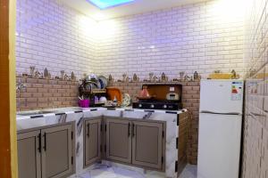 Il comprend une cuisine dotée de murs en briques blanches et d'un réfrigérateur blanc. dans l'établissement aDAM, à Dakhla