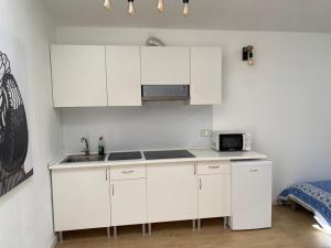 cocina blanca con fregadero y microondas en LOFT CAL XURIGUER, en Font-Rubí