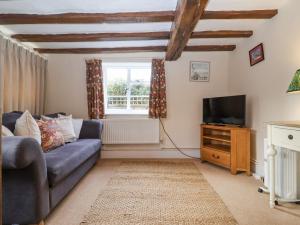 a living room with a blue couch and a tv at 2 The Almshouses in Saxmundham