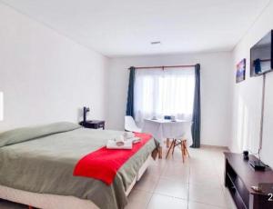 a bedroom with a bed with a red blanket and a table at Newen Bed and breakfast in El Chalten