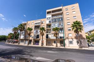 an apartment building with palm trees in front of a street at Apartments DREAM in Málaga