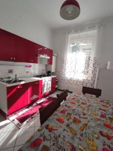 eine Küche mit roten Schränken und einem großen Tisch mit Stühlen in der Unterkunft Lucia appartamento uso esclusivo - Aeroporto Genova Sestri Ponente in Genua