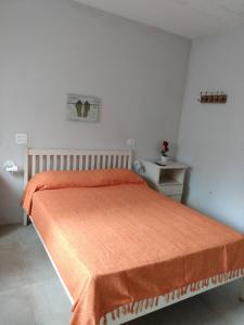 a bedroom with a bed with an orange blanket on it at Vila Juma in Camburi