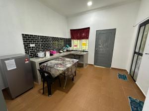 a small kitchen with a table and a refrigerator at Dhia Homestay2 in Machang