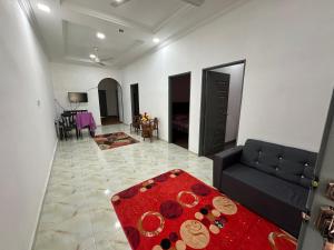 a living room with a black couch and a red rug at Dhia Homestay2 in Machang