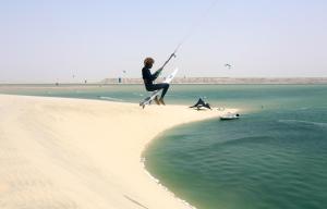 een man springt in het water op een strand bij aDAM in Dakhla