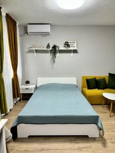 ein Schlafzimmer mit einem Bett und einem gelben Sofa in der Unterkunft Central Studio Apartment - Varna City in Warna