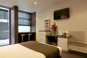 a hotel room with a bed and a desk and a television at Zero Davey Boutique Apartment Hotel in Hobart