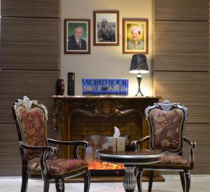 een woonkamer met 2 stoelen, een tafel en een open haard bij Hotel Seever in Erbil