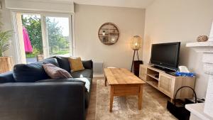 a living room with a couch and a tv at La Villa des Lilas in Saint-Valery-sur-Somme