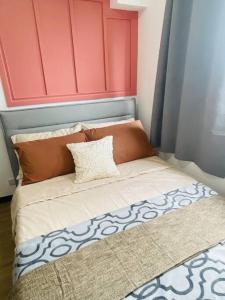 uma cama com uma cabeceira vermelha com uma almofada em The Pink House em Davao