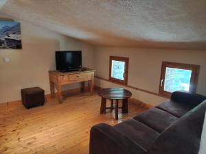 a living room with a couch and a tv at Chalet Le Grand Méan in Bonneval-sur-Arc