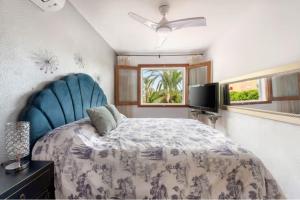 a bedroom with a bed with a blue headboard and a television at CASA ISA BEACH, 1 minute to the beach in Puebla de Farnals