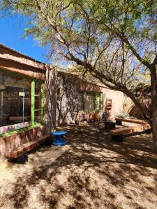 un bâtiment en pierre avec des bancs et un arbre dans l'établissement Cabaña Pimientos, à San Pedro de Atacama