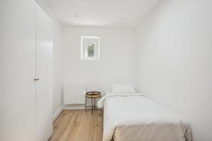 een witte slaapkamer met een bed en een tafel bij Maison moderne parisienne in Colombes