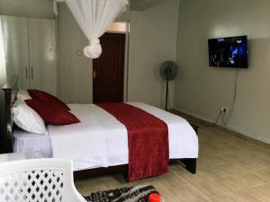 um quarto com uma cama com um cobertor vermelho e branco em Milimani Comfort em Kisumu