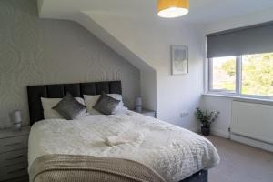a bedroom with a bed with a white comforter and a window at Spacious home sleeps 13 guests Shirley in Solihull