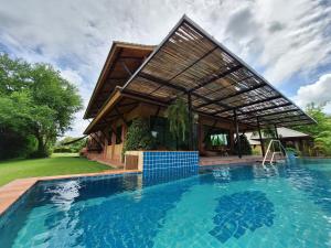 a house with a swimming pool in front of a house at Chalala villa with bio-pool & Sala! in Chiang Mai