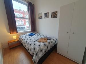 um pequeno quarto com uma cama e uma janela em 63B Willesden Lane Two Bed Apartment em Londres