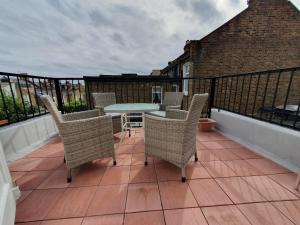um pátio com cadeiras e uma mesa na varanda em 63B Willesden Lane Two Bed Apartment em Londres