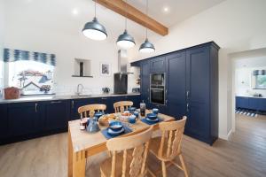 uma cozinha com armários azuis e uma mesa de madeira com cadeiras em Courtyard Cottage em Barnstaple