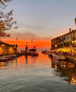 a river with boats in a city at sunset at Casa Peppa in Lazise