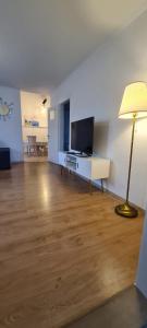 a living room with a flat screen tv and a lamp at Edel Apartments Dulliken in Dulliken