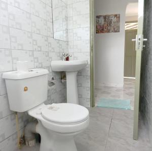 a white bathroom with a toilet and a sink at MILIMANI DRIVE LIVINGs in Kisumu