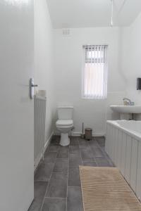 a bathroom with a toilet and a tub and a sink at Modern 4bedroom Spacious Family Home in Liverpool