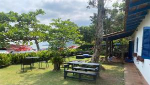 een groep tafels en stoelen in een tuin bij Suítes Pé na Areia in Barra do Sahy